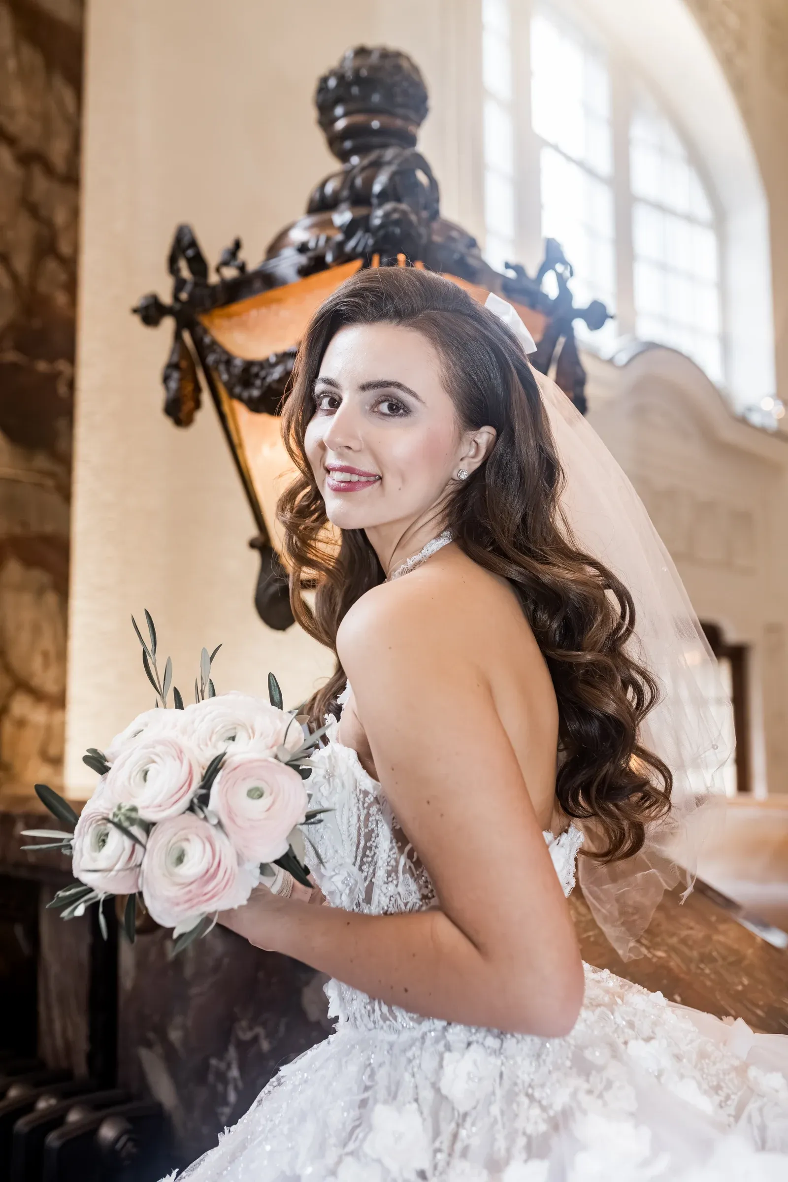 Braut im Brautkleid mit Braustrauß auf großer Treppe