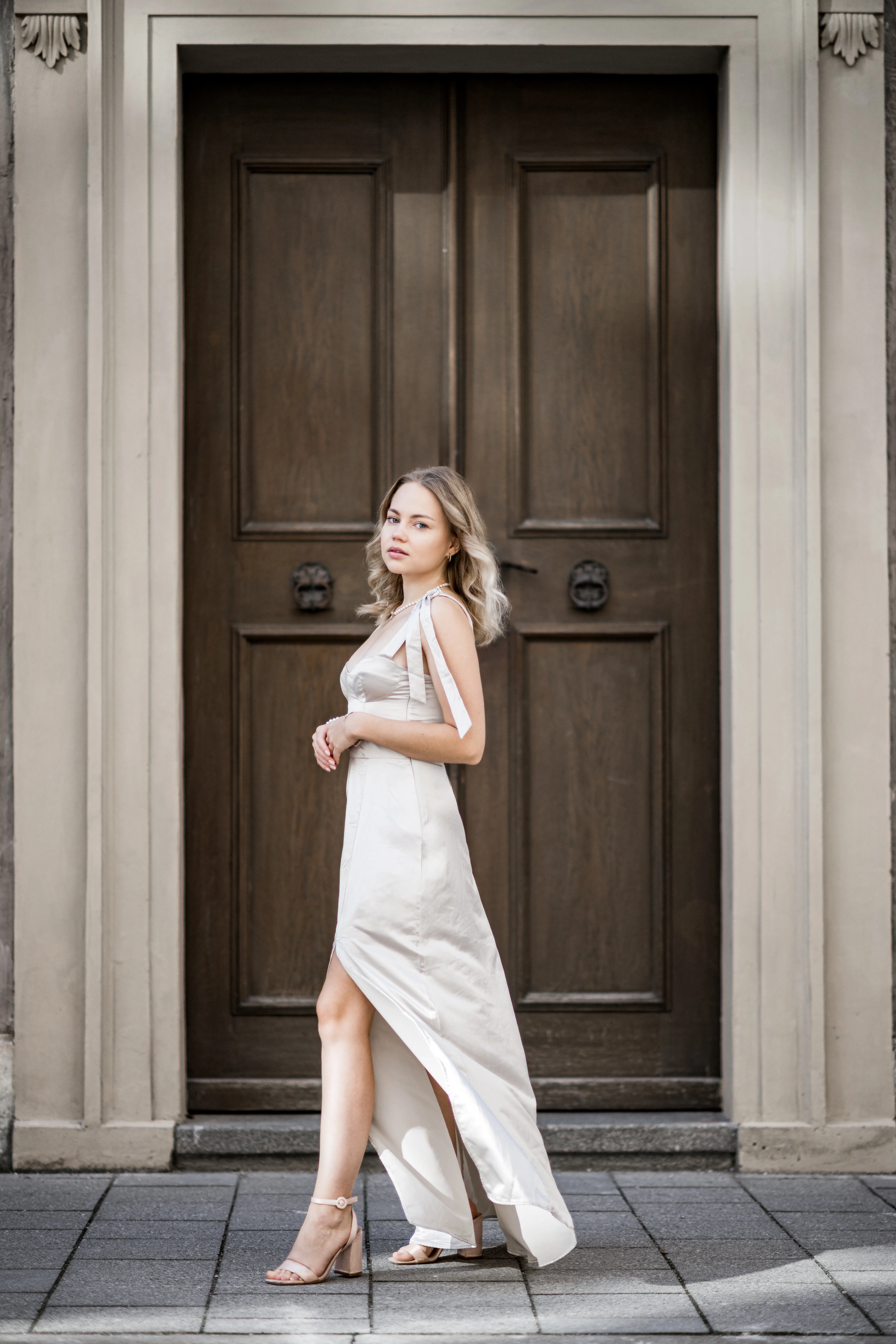 Model im Abendkleid posiert vor einer großen Holztür